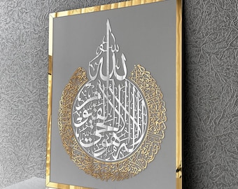 Puede incluir: Una pieza de arte de pared enmarcada en oro con un diseño de caligrafía árabe plateado. El diseño presenta un círculo central con patrones intrincados y la palabra "Allah" en escritura árabe.