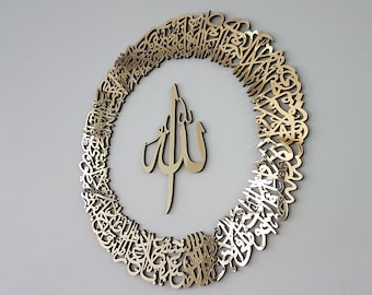 Op de afbeelding: Een gouden metalen wanddecoratie met een cirkelvormig ontwerp met ingewikkelde Arabische kalligrafie rond een centraal symbool van het woord "Allah" in Arabisch schrift.