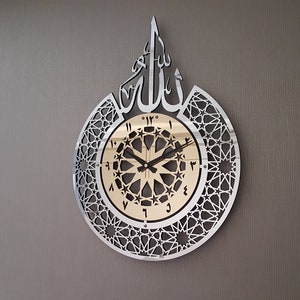 May include: A silver and gold wall clock with Arabic numerals and a geometric design. The clock features the word "Allah" in Arabic script.