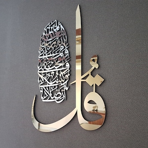 May include: A gold-colored metal wall art piece featuring intricate Arabic calligraphy. The design is a combination of a vertical line and a curved shape, with the calligraphy filling the space between them.