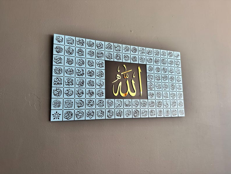 Puede incluir: Arte mural rectangular con caligraf&iacute;a &aacute;rabe. La obra de arte tiene un fondo azul claro con numerosos cuadrados de escritura negros. Un cuadrado central marr&oacute;n muestra la palabra "Allah" en color dorado.