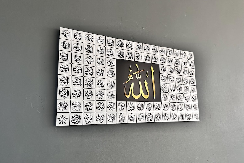 Puede incluir: Arte mural rectangular con caligraf&iacute;a &aacute;rabe. La obra tiene un fondo blanco con escritura negra en un patr&oacute;n de cuadr&iacute;cula. El centro tiene un cuadrado negro con escritura &aacute;rabe dorada. Una pieza decorativa para la decoraci&oacute;n del hogar.