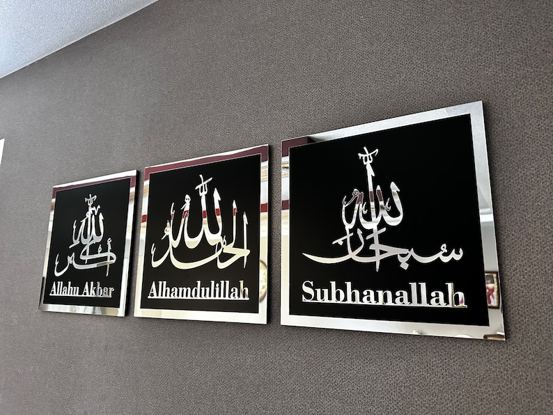 May include: Three black framed wall decor pieces with silver lettering. The lettering is in Arabic script and translates to "Allahu Akbar", "Alhamdulillah", and "Subhanallah".