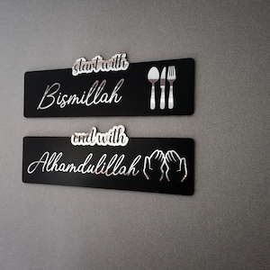 May include: Two black rectangular signs with white text and icons. The top sign says "start with Bismillah" and has a fork, knife, and spoon icon. The bottom sign says "end with Alhamdulillah" and has two hands in a praying position.