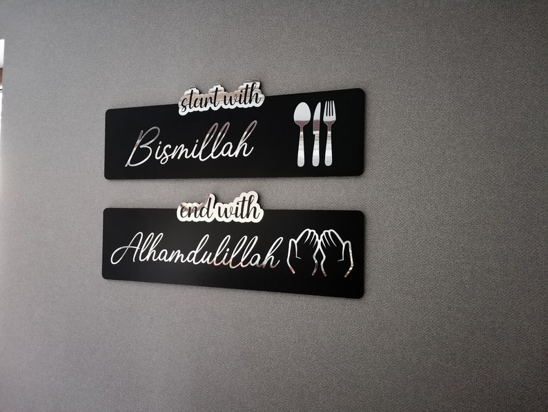 May include: Two black rectangular signs with white text and icons. The top sign says "start with Bismillah" and has a fork, knife, and spoon icon. The bottom sign says "end with Alhamdulillah" and has two hands in a praying position.