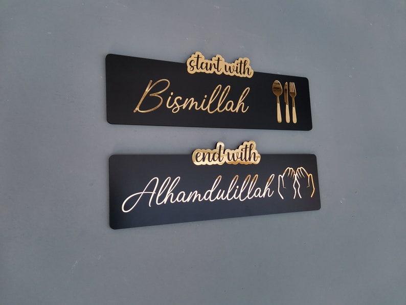 May include: Two black rectangular signs with gold lettering. The top sign says "start with Bismillah" and has a gold fork, knife, and spoon. The bottom sign says "end with Alhamdulillah" and has two gold hands in a praying position.
