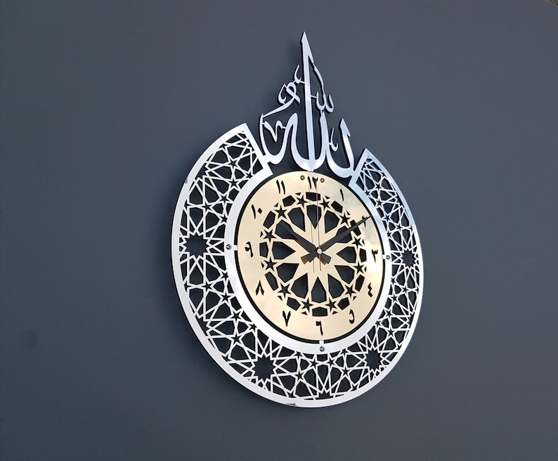 May include: A silver and gold clock with Arabic numerals and a geometric design. The clock face features the word "Allah" in Arabic calligraphy.