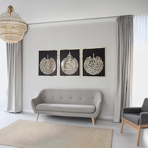 May include: Three framed black wall art pieces with gold calligraphy. The art is displayed above a gray sofa in a modern living room setting. A large, round chandelier hangs from the ceiling, and a neutral-toned rug is on the floor.