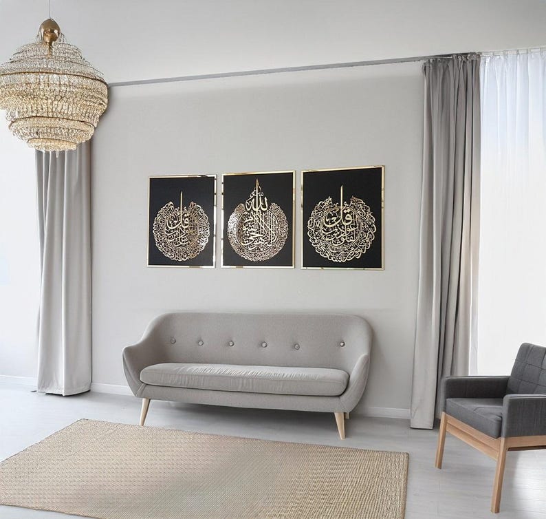 May include: Three framed black wall art pieces with gold calligraphy. The art is displayed above a gray sofa in a modern living room setting. A large, round chandelier hangs from the ceiling, and a neutral-toned rug is on the floor.