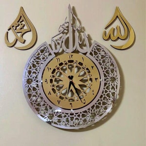 May include: A gold and silver wall clock with Arabic calligraphy and a geometric design. The clock face features Roman numerals and a starburst pattern.