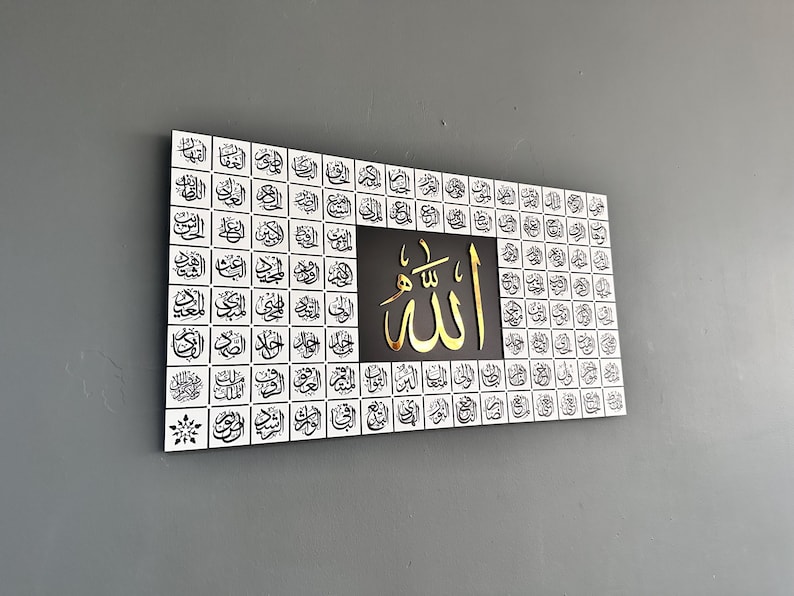 Puede incluir: Arte mural rectangular con caligraf&iacute;a &aacute;rabe. La obra presenta un fondo blanco con escritura negra dispuesta en un patr&oacute;n de cuadr&iacute;cula. El panel central es negro con texto &aacute;rabe dorado. La palabra "Allah" se muestra de forma destacada.