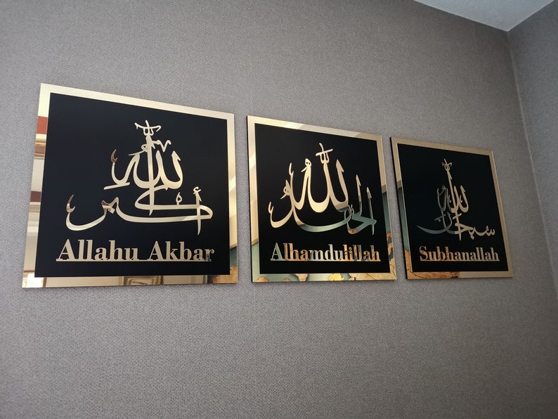 May include: Three gold framed wall plaques with black backgrounds and gold Arabic calligraphy. The plaques read "Allahu Akbar", "Alhamdulillah", and "Subhanallah".
