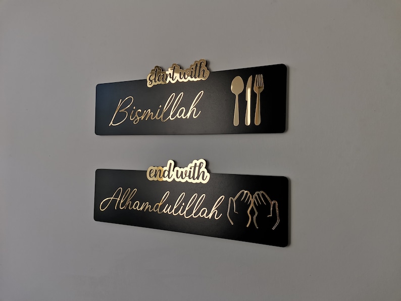 May include: Two black rectangular signs with gold lettering and icons. The top sign says "start with Bismillah" and has a gold fork, knife, and spoon. The bottom sign says "end with Alhamdulillah" and has two gold hands in a praying position.
