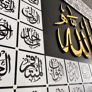 Puede incluir: Arte mural con caligraf&iacute;a &aacute;rabe en negro y dorado. La palabra &laquo;Allah&raquo; se muestra en dorado, con caligraf&iacute;a adicional en baldosas cuadradas blancas. La obra de arte est&aacute; sobre un fondo negro, creando un contraste llamativo.