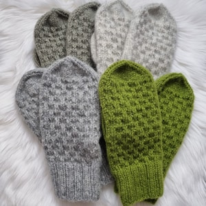 May include: A set of six knitted mittens in various shades of green and gray. The mittens are made with a textured stitch pattern.