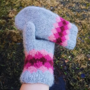 May include: A pair of gray knitted mittens with pink and brown stripes. The mittens are soft and fluffy.
