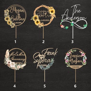 Puede incluir: Seis adornos de pastel de boda de madera. Cada adorno presenta nombres y fechas, con elementos florales y decorativos. Los dise&ntilde;os incluyen girasoles, coronas y fuentes de escritura. Los adornos est&aacute;n hechos de madera clara.