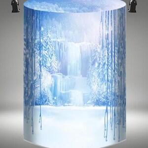 May include: A cylindrical backdrop with a winter scene featuring a waterfall and snow-covered trees. The background is a light blue with white snowflakes and a light pink sky. The bottom of the backdrop is white and appears to be snow.