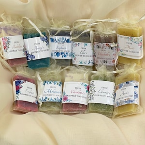 May include: Ten small bars of soap wrapped in sheer fabric bags with personalized labels. Each label features a floral design and the text "From [Name]'s Shower to Yours".