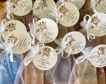 May include: A collection of small, wrapped soaps in various colors, each adorned with a round tag. The tags feature a cartoon deer illustration and the text "Thank You For Showering Mira With Love!" tied with white ribbon.