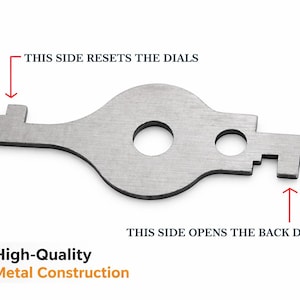 May include: A flat, silver-colored metal tool with a central circular cutout and a smaller circular hole. One end is labeled with text reading THIS SIDE RESETS THE DIALS, while the other end is labeled with text reading THIS SIDE OPENS THE BACK DOOR.