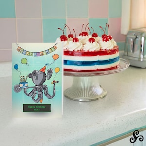 May include: A birthday card with a robot illustration holding a cake and balloons, with the text "Happy Birthday Mum!" A layered red, white, and blue cake topped with whipped cream and cherries sits on a glass cake stand.