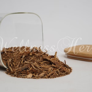 May include: A glass jar with a wooden lid, filled with brown, shredded bark. The jar is tipped over, spilling the bark onto a white surface.