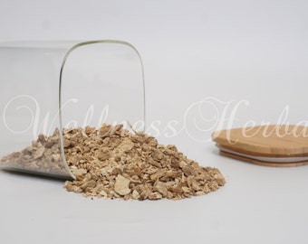 May include: A glass jar with a bamboo lid filled with dried, light brown, chopped herbs. The jar is tipped over and the herbs are spilling out onto a white surface.