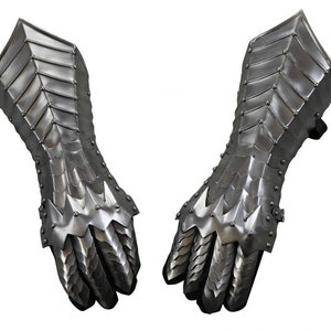 May include: A pair of silver metal gauntlets with a spiky design. The gauntlets are made of interlocking plates and have a pointed finger design.