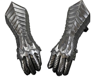 May include: A pair of silver metal gauntlets with a spiky design. The gauntlets are made of interlocking plates and have a pointed finger design.