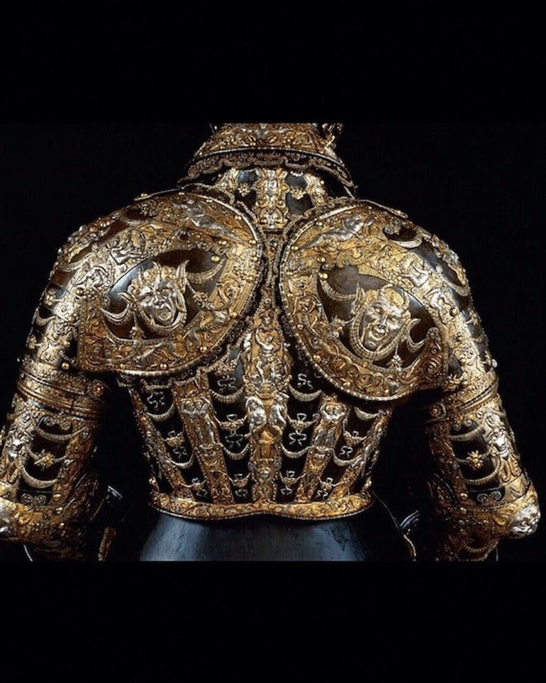 K&ouml;nnte beinhalten: Eine detailreiche, verzierte R&uuml;stung mit goldenen und silbernen Verzierungen. Die R&uuml;stung ist mit komplizierten Mustern und grotesken Gesichtern verziert.