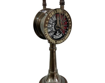 May include: Brass ship's wheel telegraph with a black and white dial and gold lettering. The dial reads "Chadba Ms" and "Liverpool-1906-London". The wheel has two wooden handles.