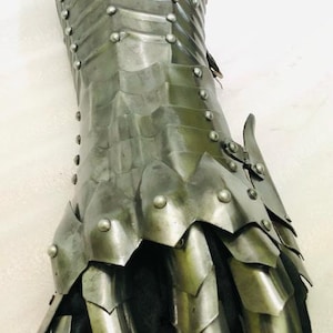 May include: A silver metal gauntlet with a segmented design and rivets. The gauntlet has a black leather lining and covers the entire hand and wrist.