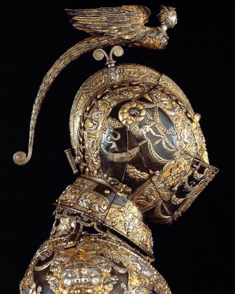 K&ouml;nnte beinhalten: Ein detaillierter, verzierter Helm aus Gold und Silber mit einer gefl&uuml;gelten Figur auf der Oberseite. Der Helm ist mit komplizierten Mustern und Designs verziert.