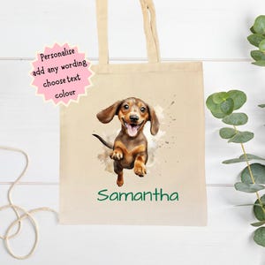 Peut inclure: Un sac fourre-tout en toile beige avec une illustration &agrave; l'aquarelle d'un chien teckel et le nom "Samantha" en vert. Le sac a de longues poign&eacute;es beiges et une &eacute;toile rose avec le texte "Personnalisez ajoutez n'importe quel libell&eacute; choisissez la couleur du texte".