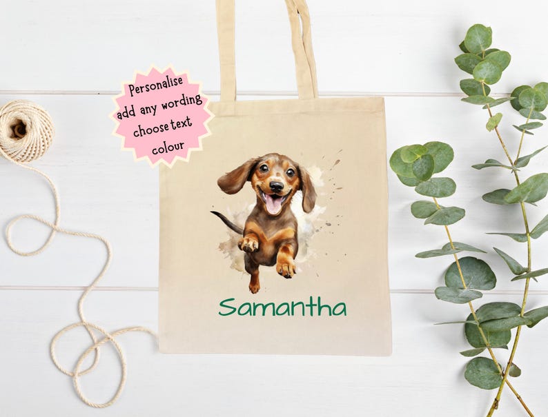 Peut inclure: Un sac fourre-tout en toile beige avec une illustration &agrave; l'aquarelle d'un chien teckel et le nom "Samantha" en vert. Le sac a de longues poign&eacute;es beiges et une &eacute;toile rose avec le texte "Personnalisez ajoutez n'importe quel libell&eacute; choisissez la couleur du texte".