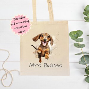 Peut inclure: Sac fourre-tout en toile beige avec une illustration &agrave; l'aquarelle d'un teckel. Le chien est marron et beige avec une expression joyeuse. Le nom "Mrs Baines" est imprim&eacute; en dessous. Une &eacute;toile rose indique "Personnalisez, ajoutez n'importe quel texte, choisissez la couleur du texte".