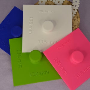 Può includere: Quattro modelli quadrati in plastica blu, verde, bianco e rosa con un cerchio rialzato al centro. I modelli sono etichettati con il testo "Fledermaht" e misure in millimetri. Le misure sono 105 mm, 110 mm, 115 mm e 105 mm.