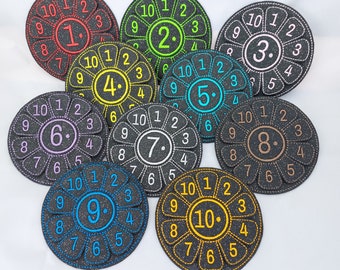 May include: Ten colorful felt circles with numbers 1 through 10, each with a flower design and a black stitched border.
