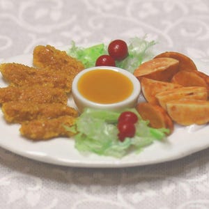 May include: A miniature plate of food featuring breaded chicken strips, potato wedges, a small bowl of dipping sauce, lettuce, and red berries. The food is arranged on a white plate, set against a white floral patterned background.