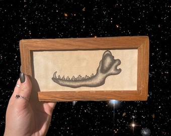 May include: A framed black and white illustration of a jawbone with teeth. The frame is made of dark wood.