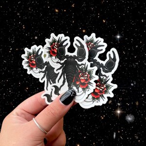 Peut inclure: Cinq autocollants noirs et blancs repr&eacute;sentant un scorpion avec des roses rouges. Le scorpion est dans un style de tatouage classique.