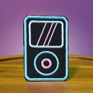 May include: A black and blue embroidered patch of a vintage MP3 player with a pink circle in the center.