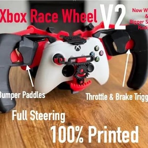 May include: A white and black Xbox controller mounted in a red and black 3D printed race wheel attachment. Text on the image reads: Xbox Race Wheel V2, Now With Tilt & Bigger Steering Radius!, Bumper Paddles, Throttle & Brake Triggers, Full Steering, 100% Printed.