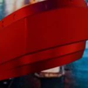 May include: A vibrant red, layered, curved object with a metallic sheen. The object has a smooth, reflective surface and appears to be part of a larger structure. The design features horizontal lines that add depth and dimension.