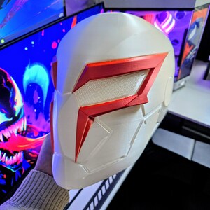 May include: A white and red helmet with a futuristic design. The helmet features a prominent red visor and accents, with a textured pattern on the visor. The overall aesthetic suggests a sci-fi or cosplay theme.