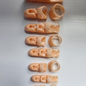 May include: Set of ten beige plastic finger splints, each with a different size and shape. The splints are designed to support and protect injured fingers.