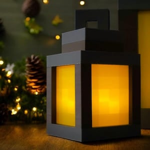 May include: A black lantern with a yellow light inside. The lantern is made of cardboard and has a Minecraft-inspired design.