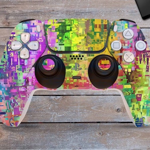 Könnte beinhalten: Ein weißer PlayStation 5 DualSense-Controller mit einem farbenfrohen, abstrakten Design. Das Design zeigt eine Mischung aus rosa, gelben, grünen und blauen Quadraten und Rechtecken.