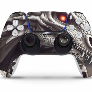 Könnte beinhalten: Ein weißer PlayStation 5-Controller mit einem Drachen-Schädel-Design. Der Controller hat ein schwarz-weißes Drachen-Schädel-Design mit einem roten Auge.